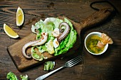 Grüner Salat mit gegrilltem Oktopus und Shrimps auf Holzbrett
