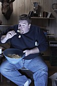 A man eating crisps in front of the television