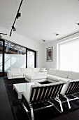 White lounge seating around low coffee table below black track lighting system with spotlights