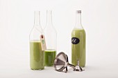 Three green smoothies in glass bottles