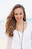 A young woman wearing a white lace cardigan over a white T-shirt