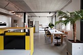 Yellow kitchen counter, long dining table and chairs in loft apartment