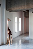 Giraffe sculpture on marble floor of modern, loft-style interior with industrial ambiance