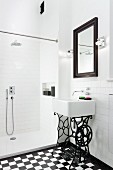 Sink on wrought iron sewing machine frame in white, modern bathroom with shower