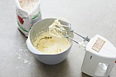 Shortbread dough in a mixing bowl with a mixer and flour