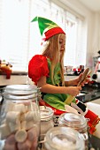 A girl dressed as a Christmas elf in a kitchen with baking utensils