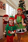 Zwei Kinder zeigen selbstgebackene Weihnachtsplätzchen