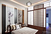 Schlafraum im japanischen Stil mit Shoji-Schiebewänden und Bambus-Zeichnungen in Nische hinter dem Doppelbett