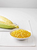 Raw corn cobs and a bowl of boiled sweetcorn