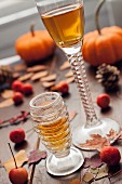 Two glasses of dessert wine with autumnal leaves and berries on a wooden table