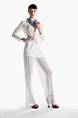 Junge Frau in Spitzenjäckchen und transparenter Marlenehose mit Modeschmuck