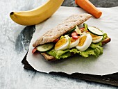 A sandwich with hard boiled eggs, tomatoes and cucumber