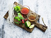 Glass noodles, herbs and sauces for Asian cuisine on a wooden board