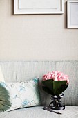 Rosenstrauss auf Sofa neben silberfarbenem Zierkissen