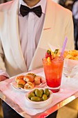 Kellner des Camparino hält ein Tablett mit Snacks und einem Drink während der Aperitivo-Zeit in Mailand
