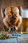 Grilled chicken on a metal stand with vegetables salad and a beer