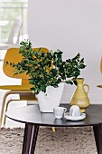 Crockery and vase of leaves on side table in front of classic chair