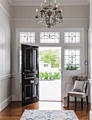 Elegant, Art-Nouveau foyer with open black front door and stained glass elements