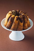 A Bundt cake on a cake stand on a brown surface