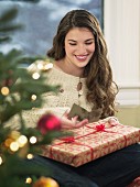 Cheerful young woman holding Christmas present