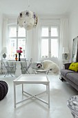 White side table on white-painted floor and seating area for two below window in modern interior