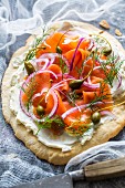 A blind-baked pizza base topped with cream cheese, smoked alpine salmon, dill, red onions and capers
