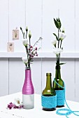 Various bottled wrapped in colourful cord and used as vases