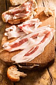 Rashers of bacon and slices of bread on a chopping board