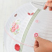 Embellishing a paper lantern with stick-on flower motifs