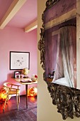 Baldachinbett spiegelt sich im Barock Spiegelrahmen, im Hintergrund moderner Tisch mit Stuhl im rosa Jugendzimmer