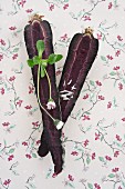 Purple carrots with daisies on a piece of floral patterned paper
