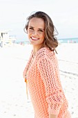 A young woman on a beach wearing an apricot coloured summer jumper