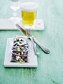 Soused herring with an apple dressing and red onion served with a glass of beer