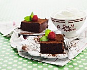 Two slices of chocolate cake with raspberries served with whipped cream