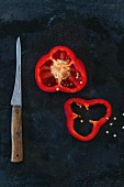 A sliced red pepper and a knife on a metal surface