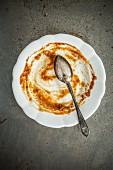 The remains of chicken curry on plate with a spoon