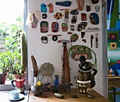 Collection of painted stones and driftwood on wall above artistic ornaments on kitchen worksurface