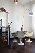 Tulip armchairs, vintage glass table and classic arc lamp next to shelves of CDs and antique mirror