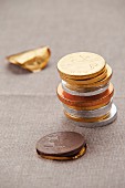 A stack of chocolate coins in foil on a tablecloth