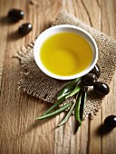 A bowl of olive oil, black olives and a spring of olive leaves