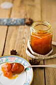 A jar of homemade apricot jam with a printed ribbon and star anise