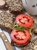 Flourless bread with sunflower, flax and chia seeds, oats, psyllium seed husks and hazelnuts, served with pesto and fresh tomatoes