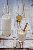 Almond milk with cinnamon and lemon zest in a bottle and a glass
