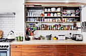 Kitchen wall cabinet with open lift-up door above spice rack and base units of recycled wood