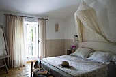 Soft natural shades in Provençal-style guest room with mosquito net and quilted bedspread (boutis) on double bed