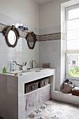Gemauerte Waschtischzeile mit zwei Waschbecken unter runden Spiegeln in renoviertem Bad mit Zementfliesenboden