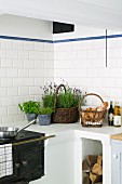 Masonry kitchen counter with integrated, antique iron cooker; potted herbs and basket of bread