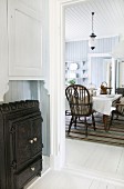 Blick von Diele mit eisernem Holzofen in Landhaus Wohnküche mit Windsor-Stühlen
