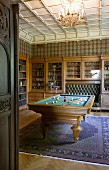 Old-fashioned room for convivial gatherings with glass-fronted cabinets, integrated leather bench, library and billiard table