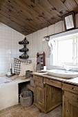 Rustic wooden washstand below window and cushions on corner of bathtub